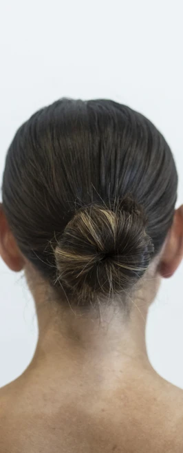 Back view of a dancer’s neatly styled bun, showing off a professional dance hairstyle against a plain white background. Back view of a dancer’s neatly styled bun, showing off a professional dance hairstyle against a plain white background.